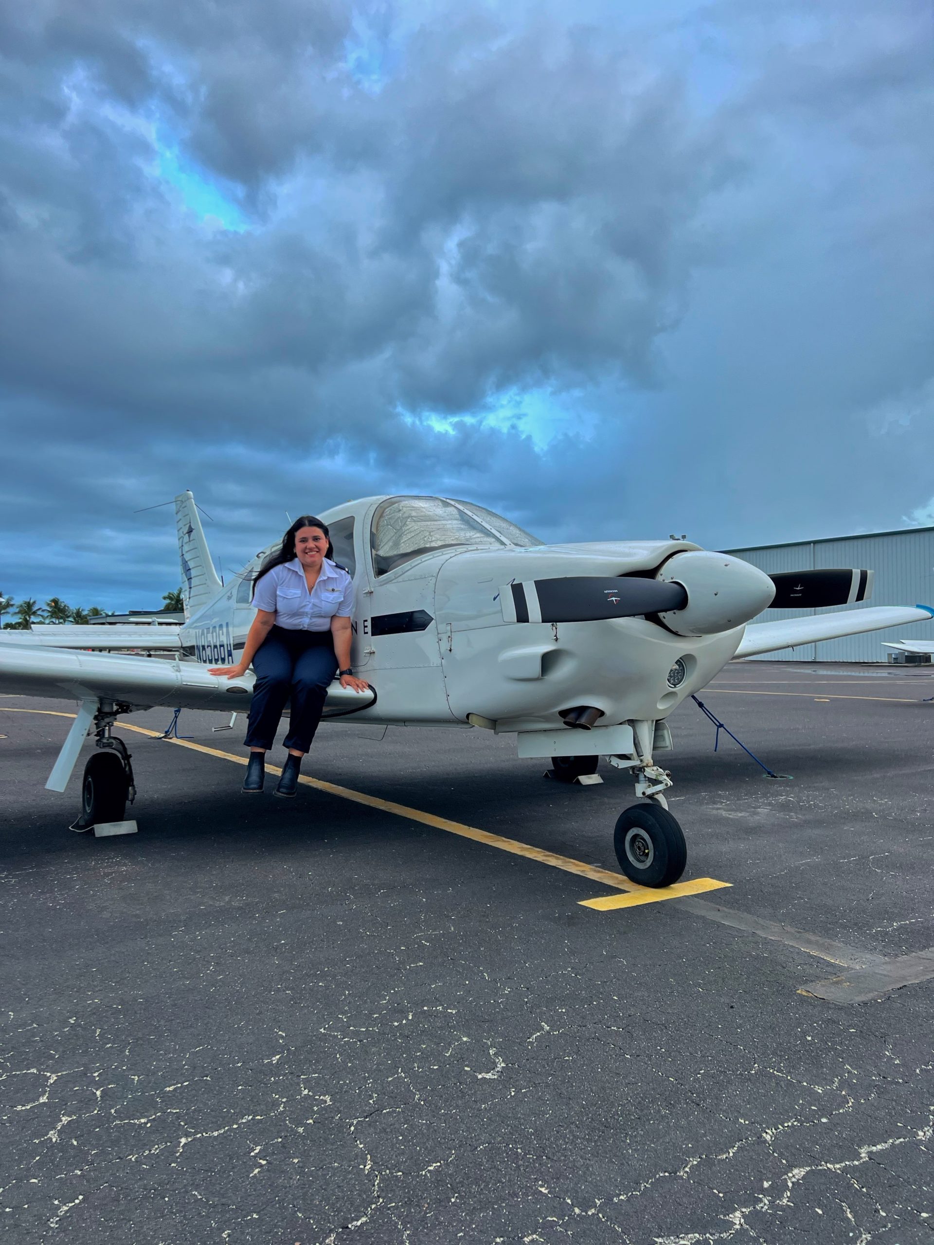 Magdiel Nathalia Caballero sitting on wing of training plane